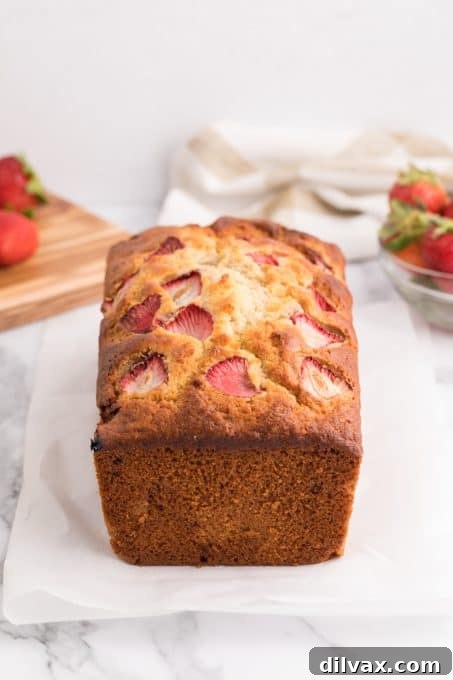 A loaf of banana bread with visible sliced strawberries on top