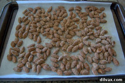 Spiced almonds spread in a single layer on a parchment-lined baking sheet