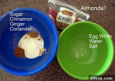 Raw almonds being tossed in egg white mixture in a bowl