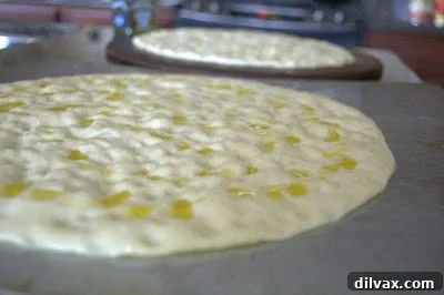 Drizzling olive oil over the dimpled dough