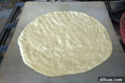Shaped flatbread dough covered with plastic wrap for a second rise