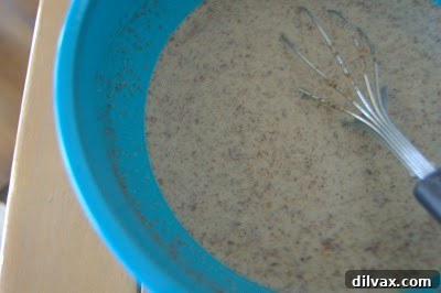 A large mixing bowl filled with the liquid and dry ingredients for the baked rice breakfast, including milk, eggs, brown rice, spices, and flaxseed meal, before the fruit is added.