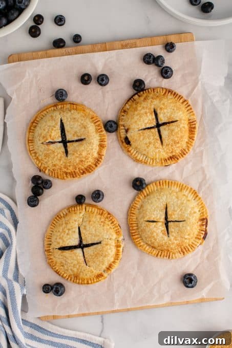 Sweet Air Fryer Blueberry Pockets 8 A batch of golden-brown hand pies cooling on a wire rack after being cooked in an air fryer.
