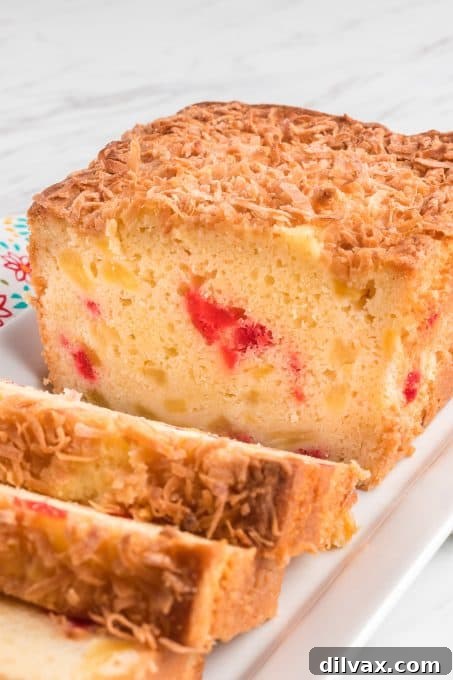 A loaf of quick bread with cherries, pineapple and coconut.