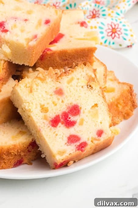 Slices of a coconut quick bread with cherries and pineapple.