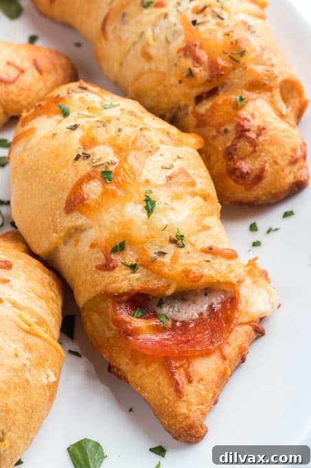 Effortless Pepperoni Crescent Rolls 3 Close-up of Pepperoni Crescent Rolls stacked on a white plate, highlighting the crispy edges.