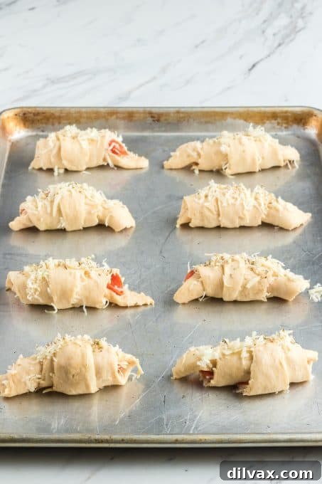 Effortless Pepperoni Crescent Rolls 6 Freshly baked Pizza Rolls arranged neatly on a baking sheet, glistening with melted cheese.