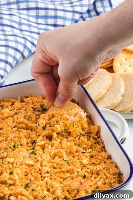 Creamy Jalapeno Popper Dip 7 Dipping a cracker into a dip with cheese, sour cream and jalapenos.
