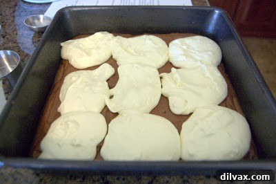 Sprinkling peanut butter chips evenly over the cream cheese and brownie layers.