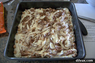 Smoothing the top surface of the marbled brownie batter with an offset spatula.