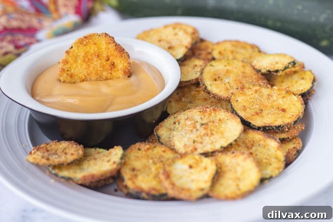 Golden Cornmeal Zucchini Crisps 2 A beautifully arranged plate of golden-brown, crispy cornmeal breaded zucchini chips, garnished with fresh herbs, ready to be served as a healthy snack or appetizer.
