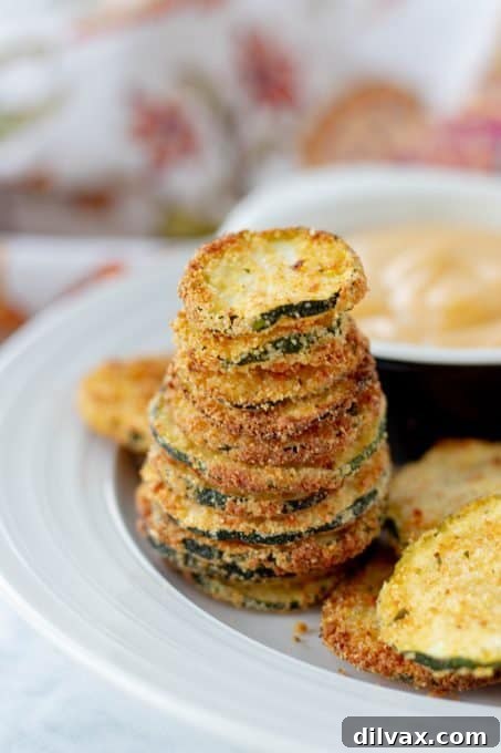 Golden Cornmeal Zucchini Crisps 6 A neatly stacked pile of perfectly air-fried or oven-baked zucchini chips, showcasing their irresistible golden-brown and crispy texture.