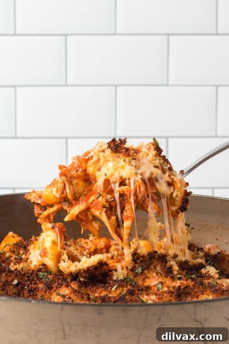 A generous spoonful of skillet chicken parmesan with gnocchi, fresh basil, and crispy topping