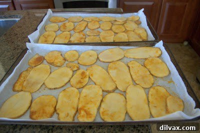 Seasoned potato slices arranged in a single layer on a parchment-lined baking sheet