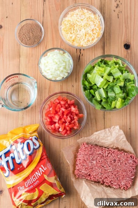 Fresh ingredients laid out for making Taco Casserole: ground beef, chips, cheese, vegetables