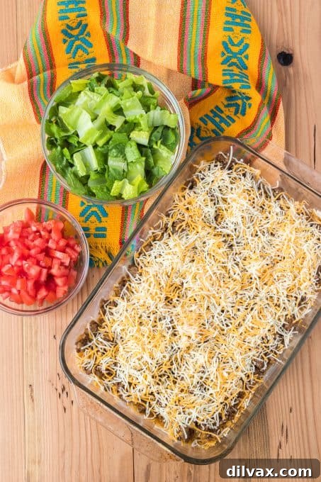 A baking dish with seasoned taco meat and cheese, ready to go into the oven