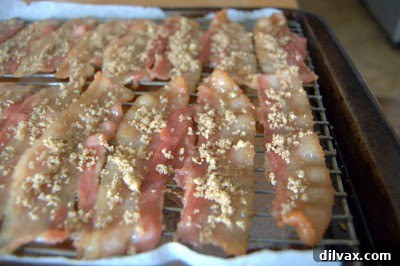 Sugared pecan bacon baking in the oven with pecans sprinkled