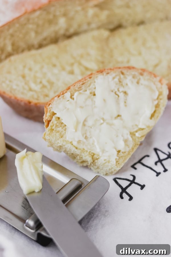 Artisan Italian Loaves 15 A slice of buttered Grandma's Italian Bread with butter melting on the knife.