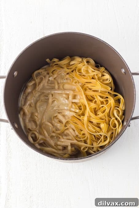 Velvety Garlic Alfredo Fettuccine 6 Fettuccine pasta and a luscious Alfredo sauce being tossed together in a large pot