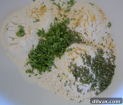 Whisking together flour, herbs, baking powder, garlic powder, and salt in a bowl.