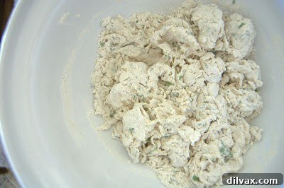 Stirring dough with a wooden spoon until it forms a cohesive ball.