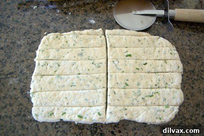 Cutting the dough rectangle into long, thin strips using a pizza cutter.