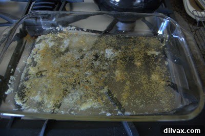 Sprinkling remaining garlic powder into the melted butter in the baking dish.