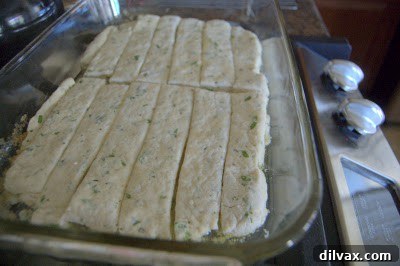 Placing dough strips into the baking dish with melted garlic butter.