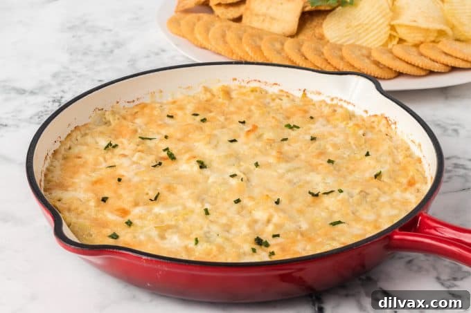 Golden brown, bubbly baked artichoke dip in a pie plate, ready to be served.