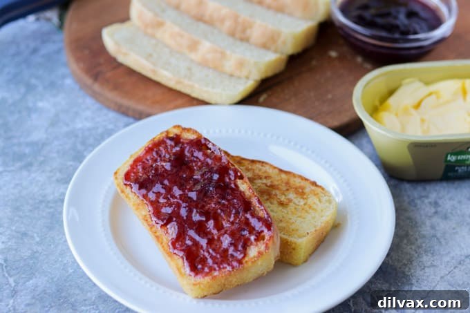 Nook and Cranny Loaf 2 Slices of golden English Muffin Bread with jam on a plate, ready to be served for breakfast.