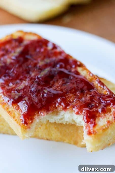 Nook and Cranny Loaf 8 A close-up shot of a slice of homemade English Muffin Bread with a bite taken out, revealing its airy and porous interior.