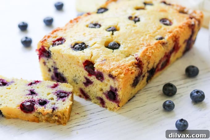 A beautifully baked loaf of Lemon Blueberry Quick Bread, garnished with fresh blueberries and lemon slices, ready to be served with coffee or tea.