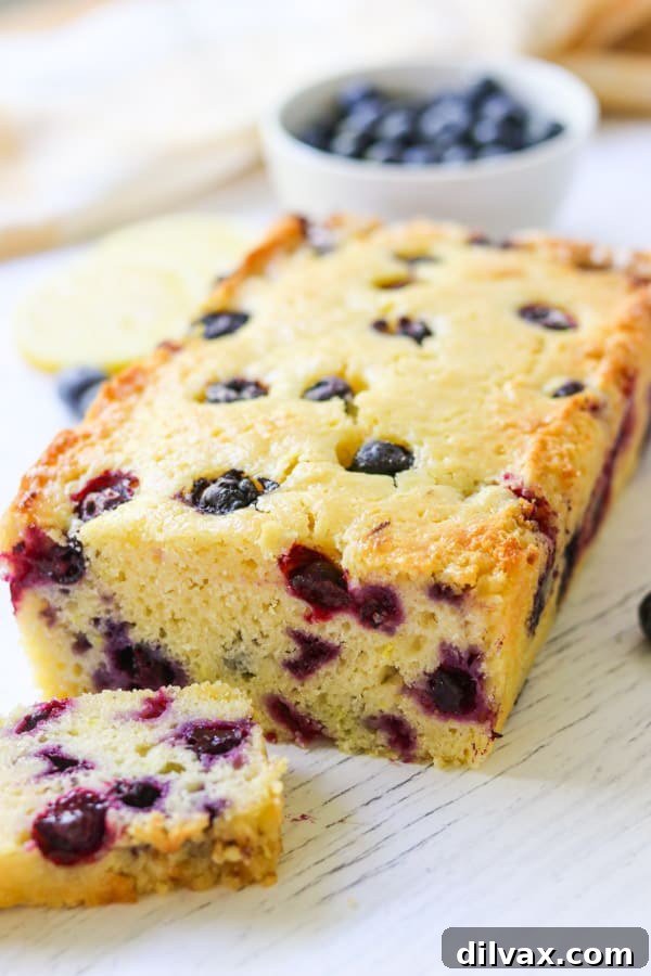 A beautifully sliced loaf of Lemon Blueberry Bread, showing its tender crumb and scattered blueberries, ready for a delicious breakfast or snack.