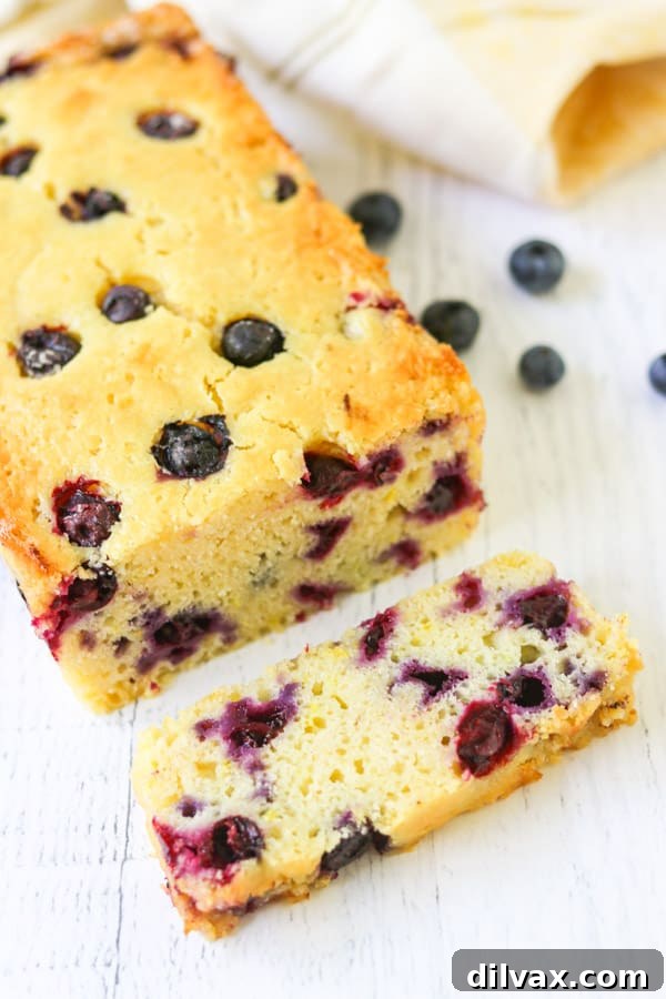 A perfect slice of Lemon Blueberry Quick Bread, rich with fruit and a golden crust, presented on a plate next to a cup of coffee, inviting you to enjoy a moment of bliss.