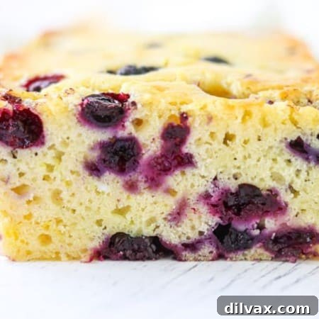 A vibrant slice of Lemon Blueberry Bread on a plate, showing juicy blueberries, perfect for a delightful snack.