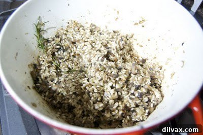 Golden Caramelized Onion and Mushroom Risotto Bake 5 A close-up of creamy mushroom risotto, elegantly presented in a bowl, garnished with green herbs and a spoon, ready to be enjoyed.