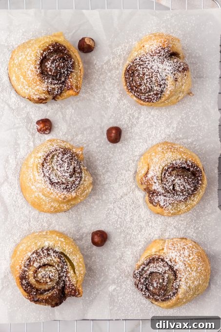 Decadent Nutella Cruffins 7 Nutella muffin croissants dusted with powdered sugar, served on a plate.