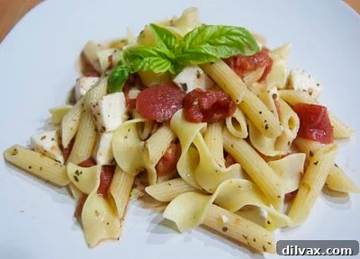 A vibrant bowl of Caprese pasta featuring cherry tomatoes, fresh mozzarella, and basil mixed with pasta.