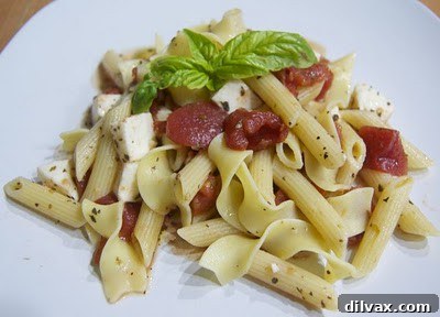 A prepared bowl of Caprese pasta, garnished with fresh basil.