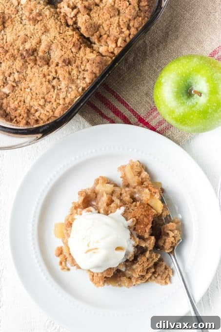 Warm Spiced Apple Crumble 7 A serving of apple crisp made with Granny Smith apples, topped with a dollop of whipped cream and a sprinkle of cinnamon.