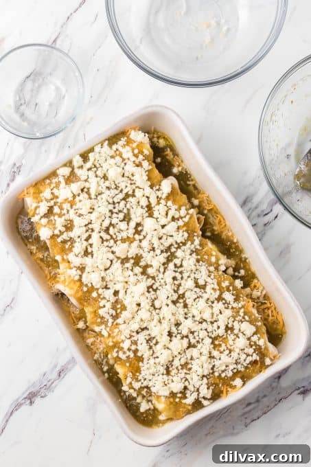 Decadent Creamy Chicken Enchiladas 7 Queso Fresco on top of a dish of enchiladas.