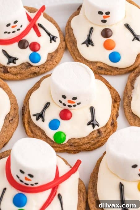 Close-up of decorative elements for the snowman cookies: regular marshmallows, red pull 'n peel licorice strings, and mini M&M's, emphasizing the vibrant colors and playful shapes.
