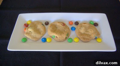 Freshly baked M&M cookies cooling on a rack, with vibrant colors peeking through.