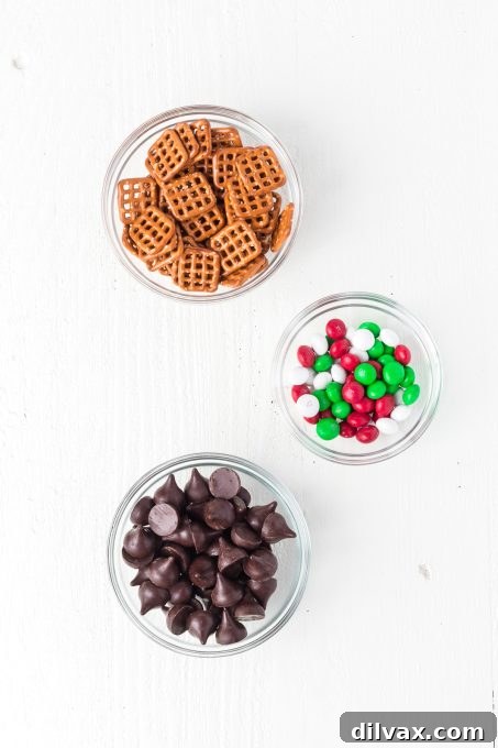 Sweet and Salty Pretzel Magic 4 Ingredients for 3 Ingredient Pretzel Hugs laid out: mint Hershey's Kisses, mint M&M's, and square pretzels.