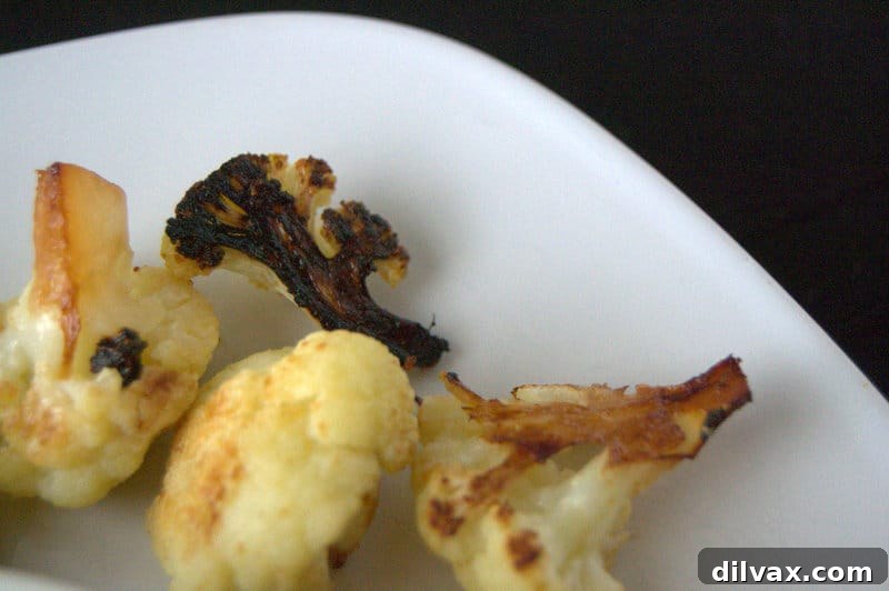 Roasted Teriyaki Cauliflower - A close-up of a single dark, crispy Teriyaki cauliflower floret on a baking sheet, highlighting its perfect roast.