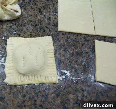 Puff pastry edges being crimped with a fork.