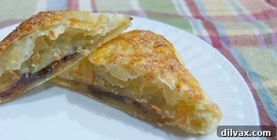 Finished golden brown Banana Nutella Puffs on a baking sheet.