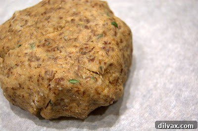 Rolling out the cracker dough between two sheets of parchment paper for even thickness.