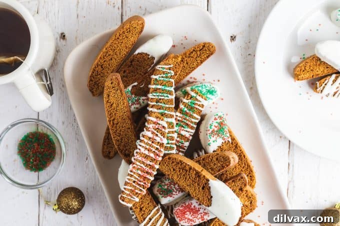 A plate of holiday gingerbread biscotti with white chocolate drizzle and festive sprinkles.