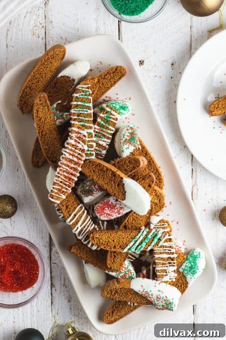 Several gingerbread biscotti, one dipped in white chocolate and decorated with sprinkles.